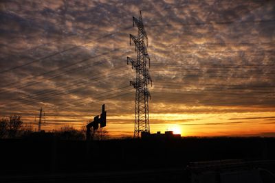 Silhouette electricity pylon on field against sky at sunset