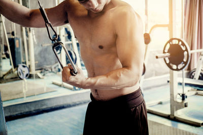 Shirtless young man exercising gym