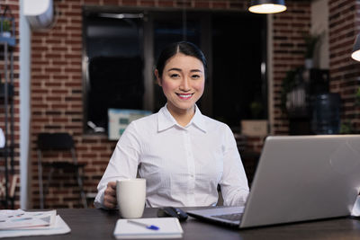 Portrait of young businesswoman with laptop sitting at office