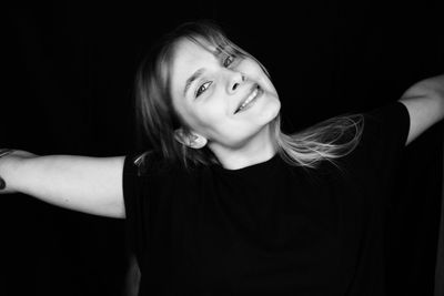 Portrait of a smiling young woman over black background