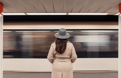 Woman standing on underground train platform in front of blurry moving train