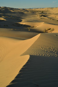 Scenic view of sand dunes against sky at sunset