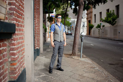 Full length of young man standing on sidewalk in city