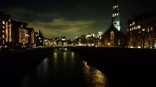 Illuminated buildings by river at night