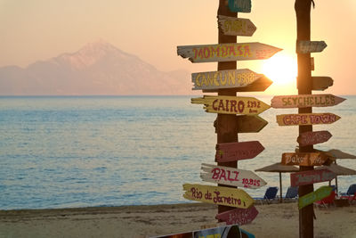 Information sign on poles at beach against sky