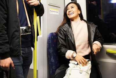 Happy woman looking at man while traveling in train