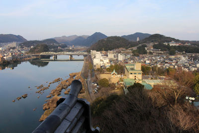 High angle view of townscape by lake against sky