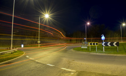 Light trails over road by street lights at night