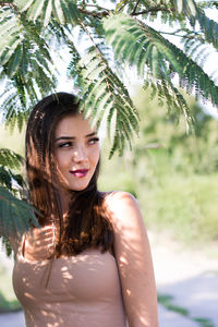 Portrait of smiling young woman against trees