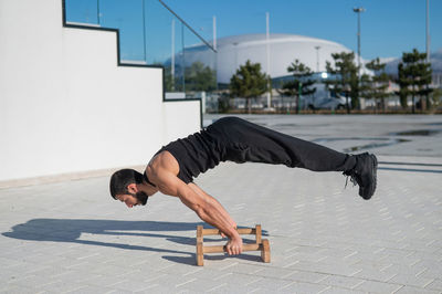 Male athlete doing handstand at street