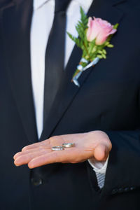 Midsection of bridegroom holding bouquet