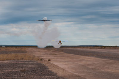 Airplane flying over landscape against sky