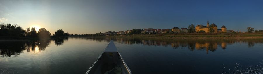 Panoramic view of lake by buildings against sky during sunset