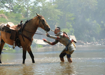 Man standing with horses in water outdoors