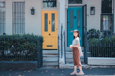 Full length of young woman standing against building