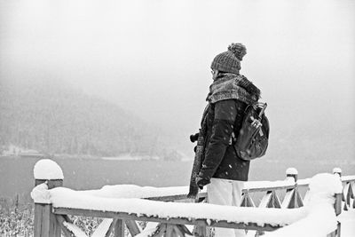 Side view of woman standing by railing during winter