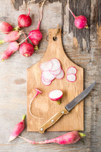 Fresh chopped radishes and a knife on a cutting board on a wooden table