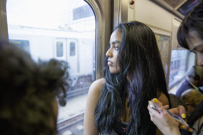 Young woman looking out the window of a train in queens, new york