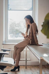 Smiling freelancer using mobile phone on desk at home office