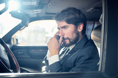 Side view of young man sitting in car