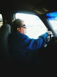 Side view of mature woman driving car