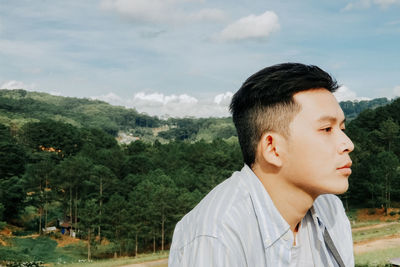 Portrait of teenage boy looking at mountains against sky