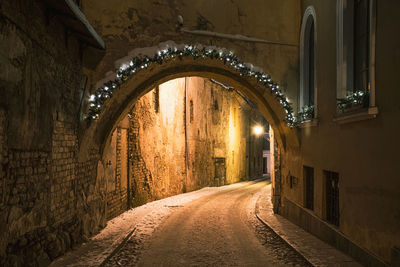 Empty road along illuminated buildings