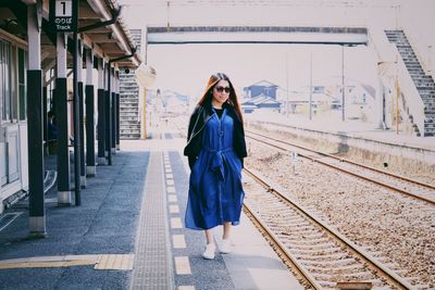 Portrait of woman standing on railroad tracks