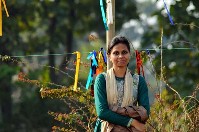 Portrait of young woman standing against plants