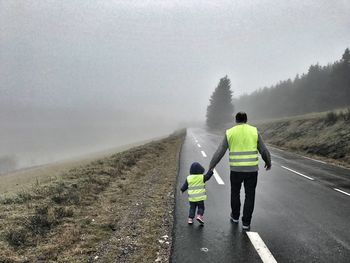 Rear view of man and child on road against sky
