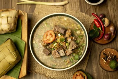 Coto makasar and ketupat, indonesian traditional food, taken with high angle view on table