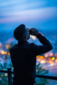 Rear view of man photographing against sky