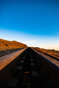 Surface level of railroad tracks against clear blue sky