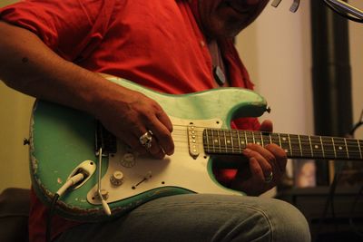 Midsection of man playing guitar