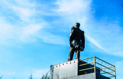 Low angle view of man standing against blue sky