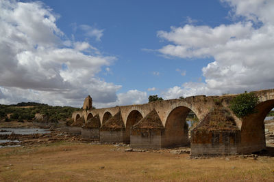Arch bridge over field against sky
