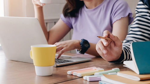 Midsection of woman using laptop on table at home