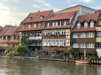 Buildings by river against sky