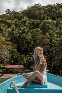 Rear view of woman sitting at poolside