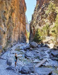 Rear view of woman on rocks by mountain