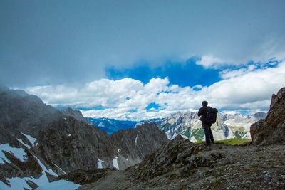 Rear view of men standing on mountain against blue sky