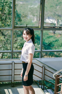 Portrait of smiling woman standing against window