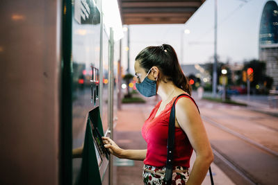 Side view of young woman looking at bus