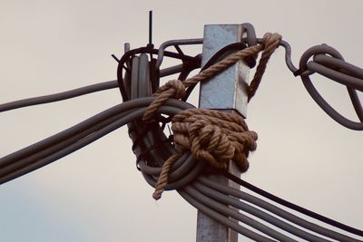 Low angle view of rope tied up against sky