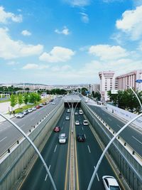 Vehicles on road against cloudy sky