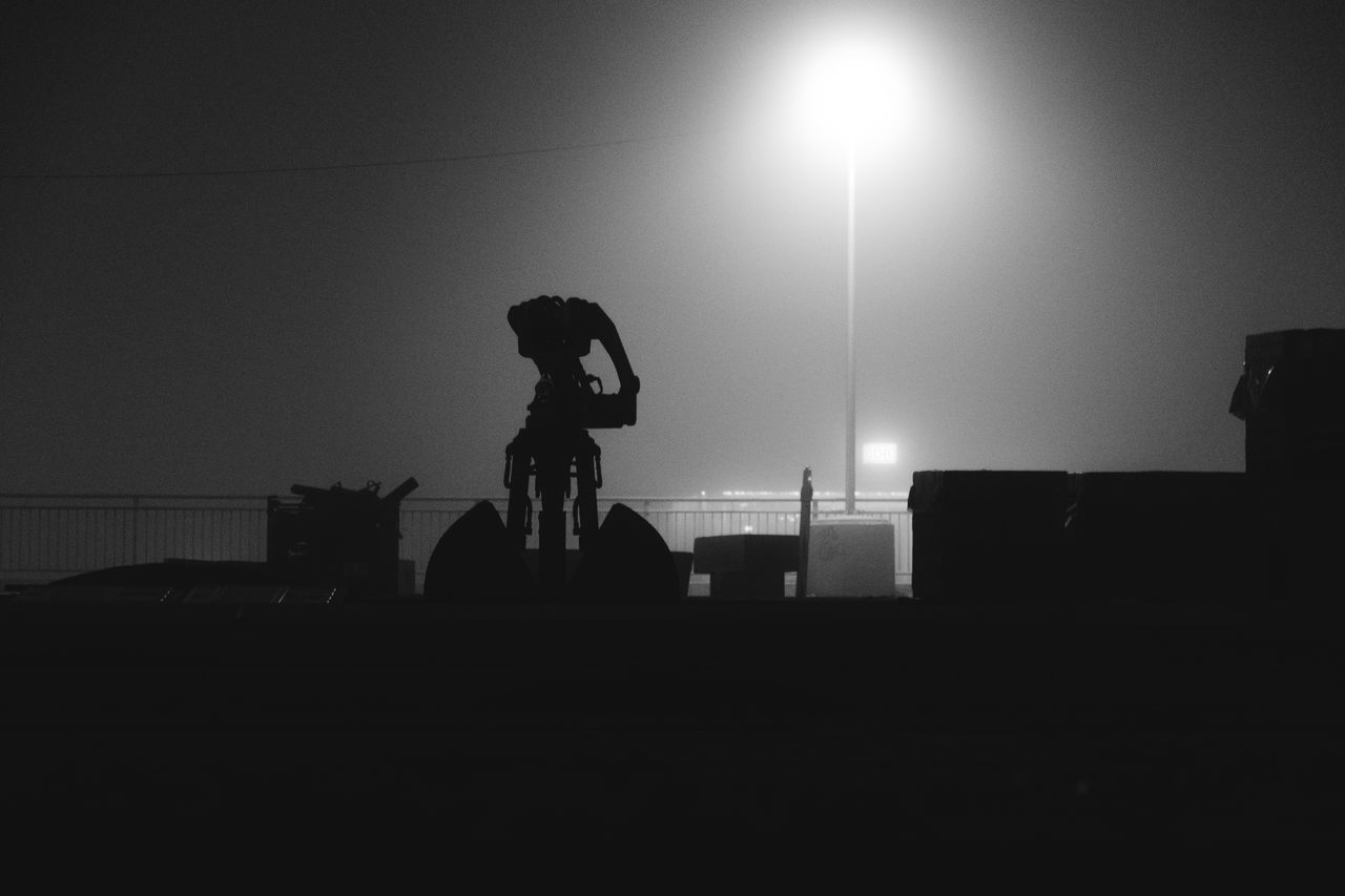 SILHOUETTE PEOPLE STANDING ON ILLUMINATED STREET AGAINST SKY AT NIGHT