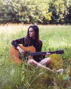 Young woman playing guitar on field