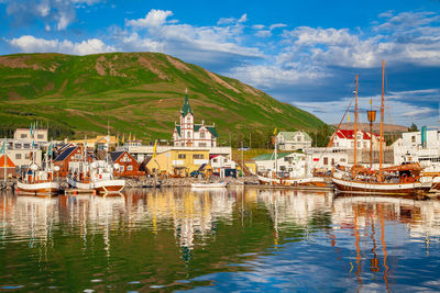 Sailboats moored in harbor against buildings in city