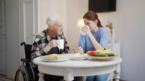 Side view of young woman drinking food at home