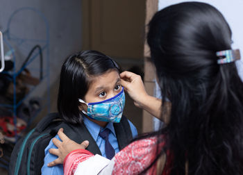 An indian mother preparing her girl child with nose mask protection to send to school after pandemic